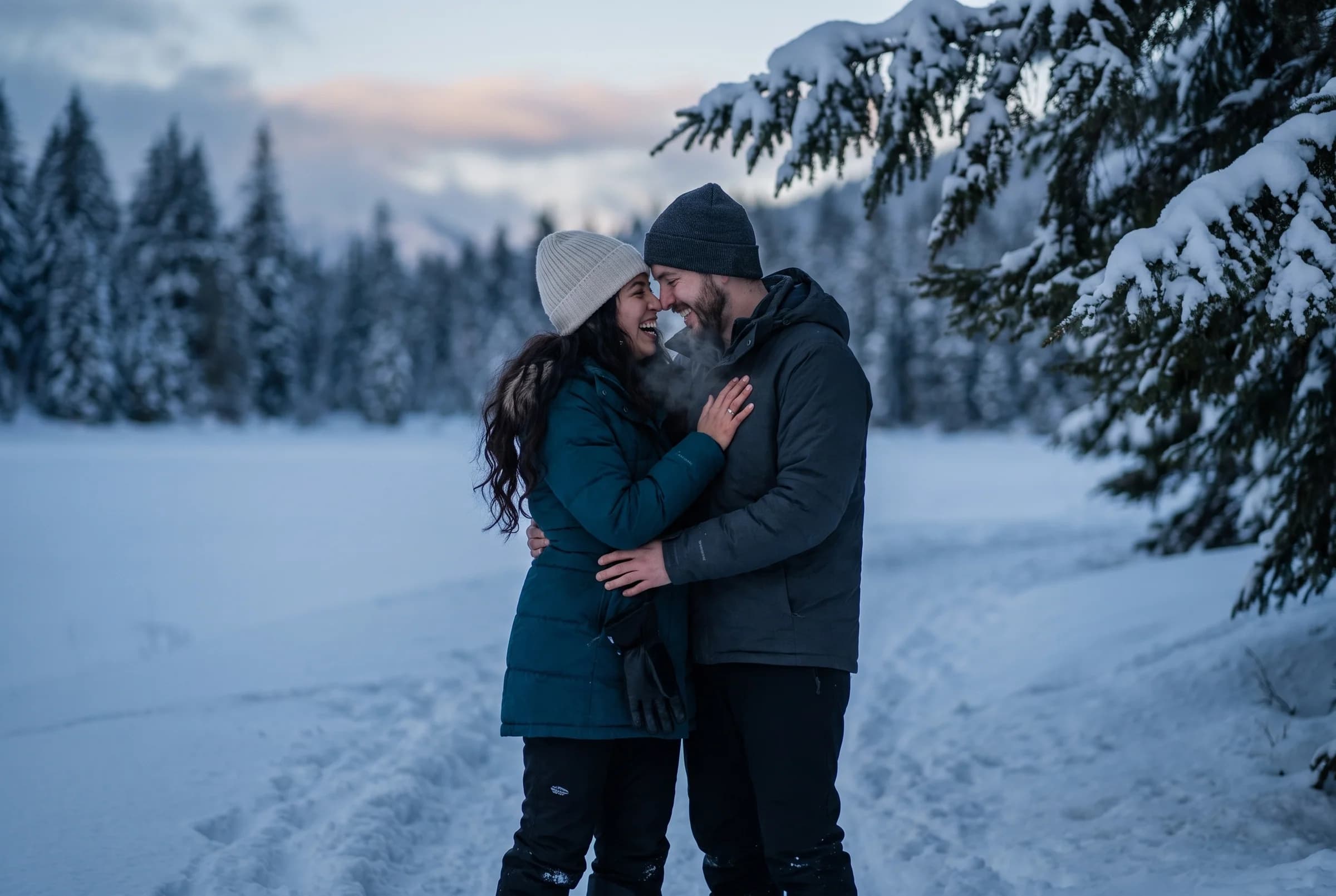Couple close together at dusk among heavily snow-laden conifers in the Callaghan Valley