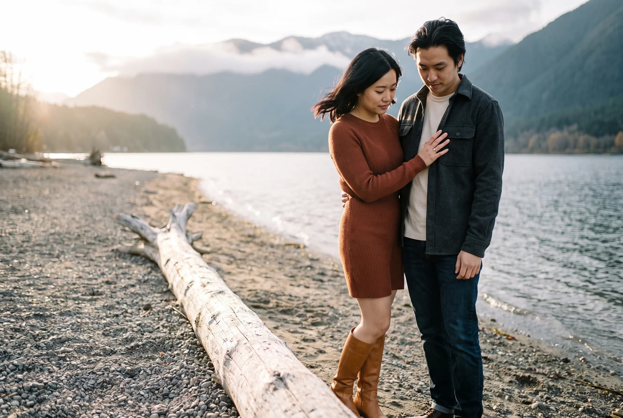 Couple standing among driftwood on the gravel shore of Alouette Lake in Golden Ears Provincial Park at sunset